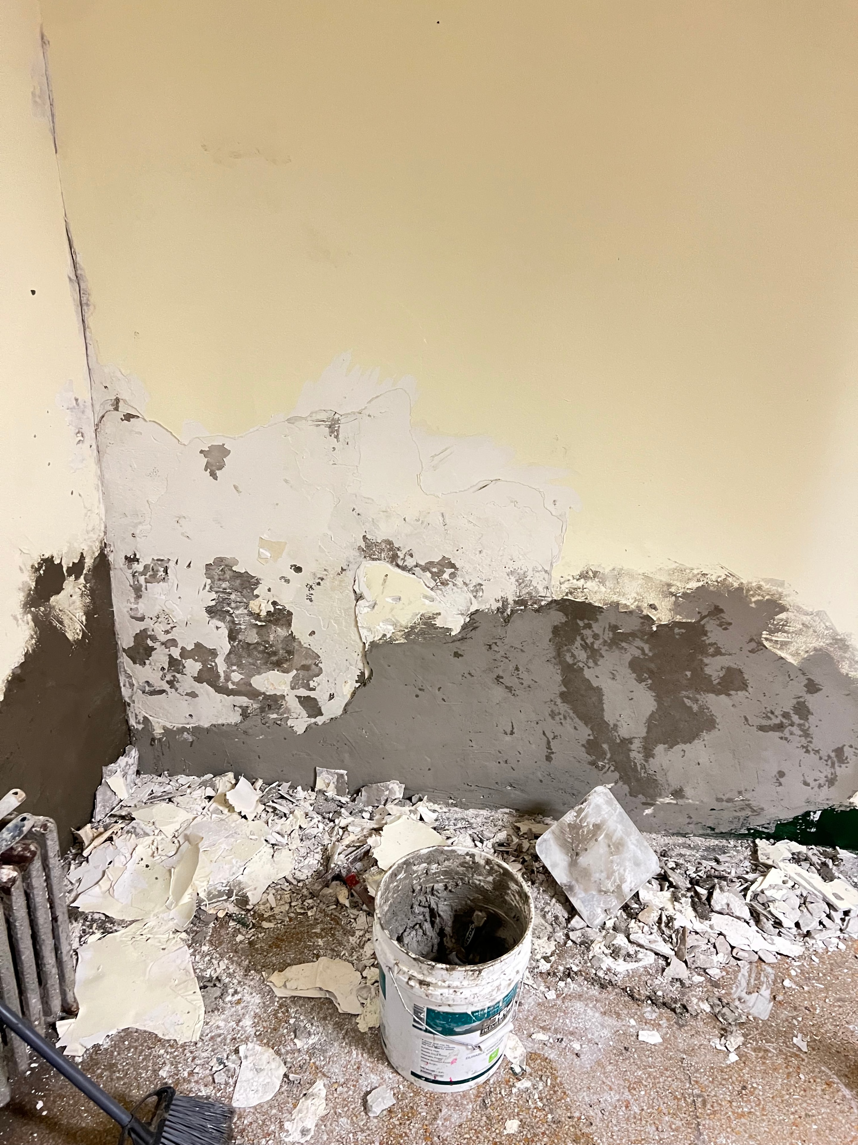 Damaged wall in an apartment building lobby before repair